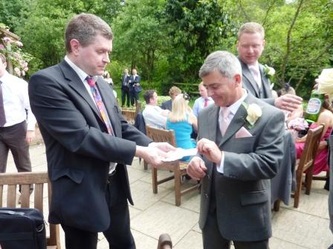 Man offering some cards to another man in a grey suit